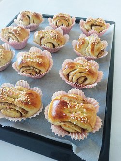 Tuoreita kanelipullia pinkeissä leivontavuoissa